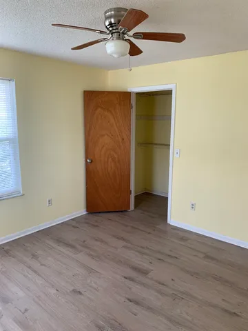 an empty room with wooden floor closet and windows