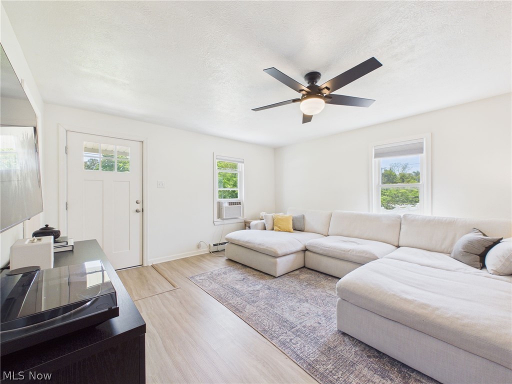 3490 County Line Road Madison, OH 44057 - Photo 17 of 42 Spacious living area featuring light wood-finish flooring, a modern ceiling fan with integrated lighting, and multiple windows providing natural light