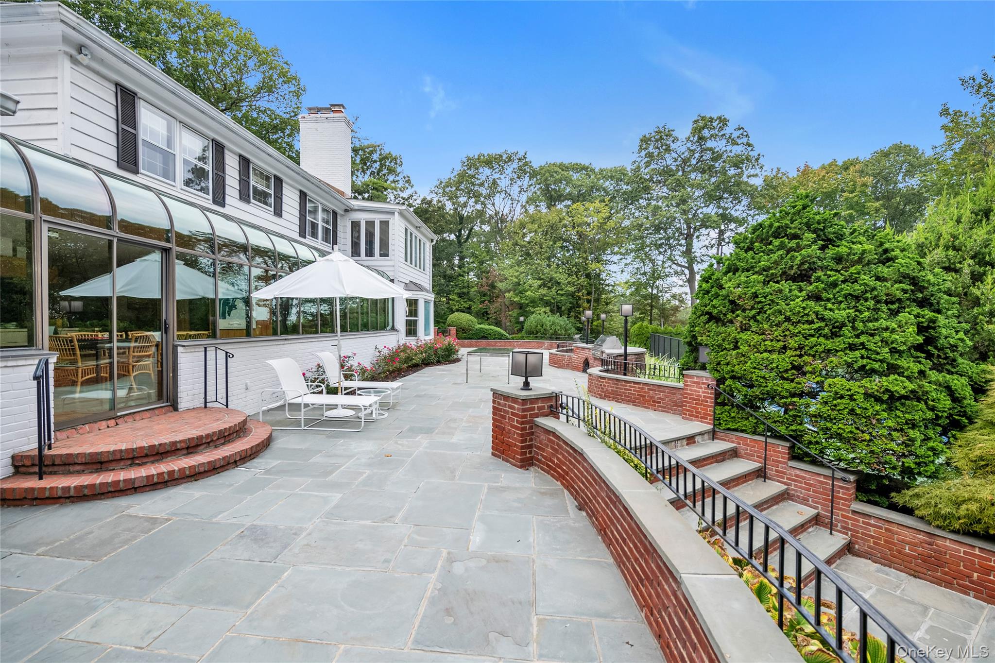45 SE Road Sands Point, NY 11050 - Photo 24 of 36 a view of a patio with a table and chairs under an umbrella