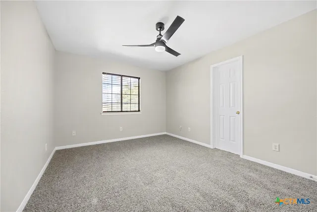 an empty room with windows and ceiling fan