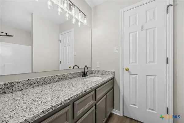 a bathroom with a granite countertop sink and a mirror