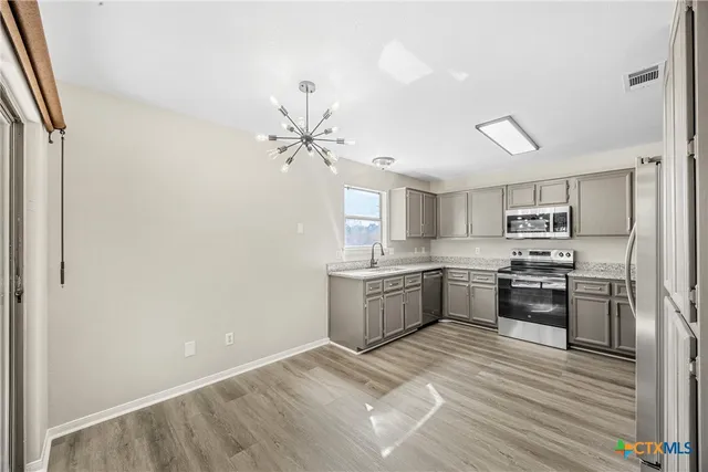 a large kitchen with cabinets wooden floor and stainless steel appliances