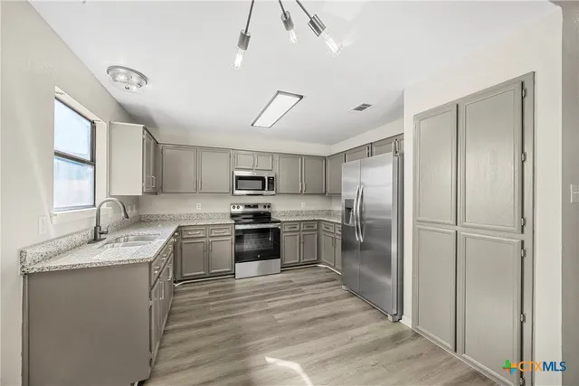 a kitchen with stainless steel appliances granite countertop a refrigerator a stove a sink and a microwave