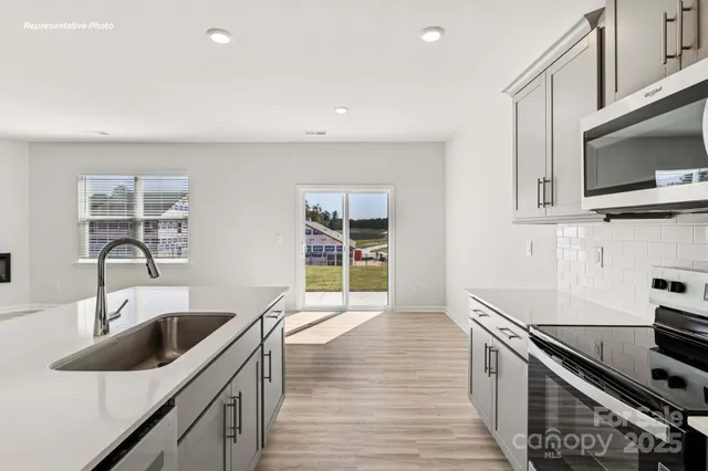 a kitchen with stainless steel appliances kitchen island granite countertop a sink and a stove top oven with wooden floor