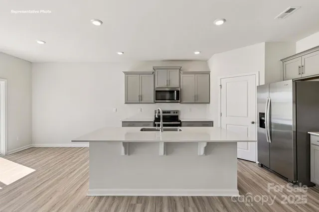 a kitchen with stainless steel appliances a refrigerator a sink a stove a microwave and cabinets