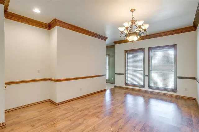 an empty room with windows and chandelier fan