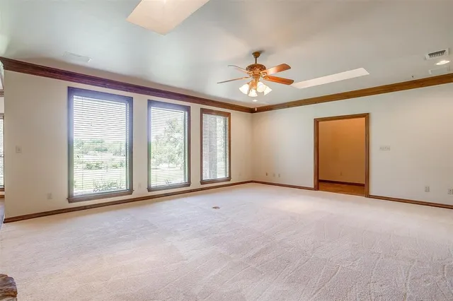 an empty room with chandelier fan and windows