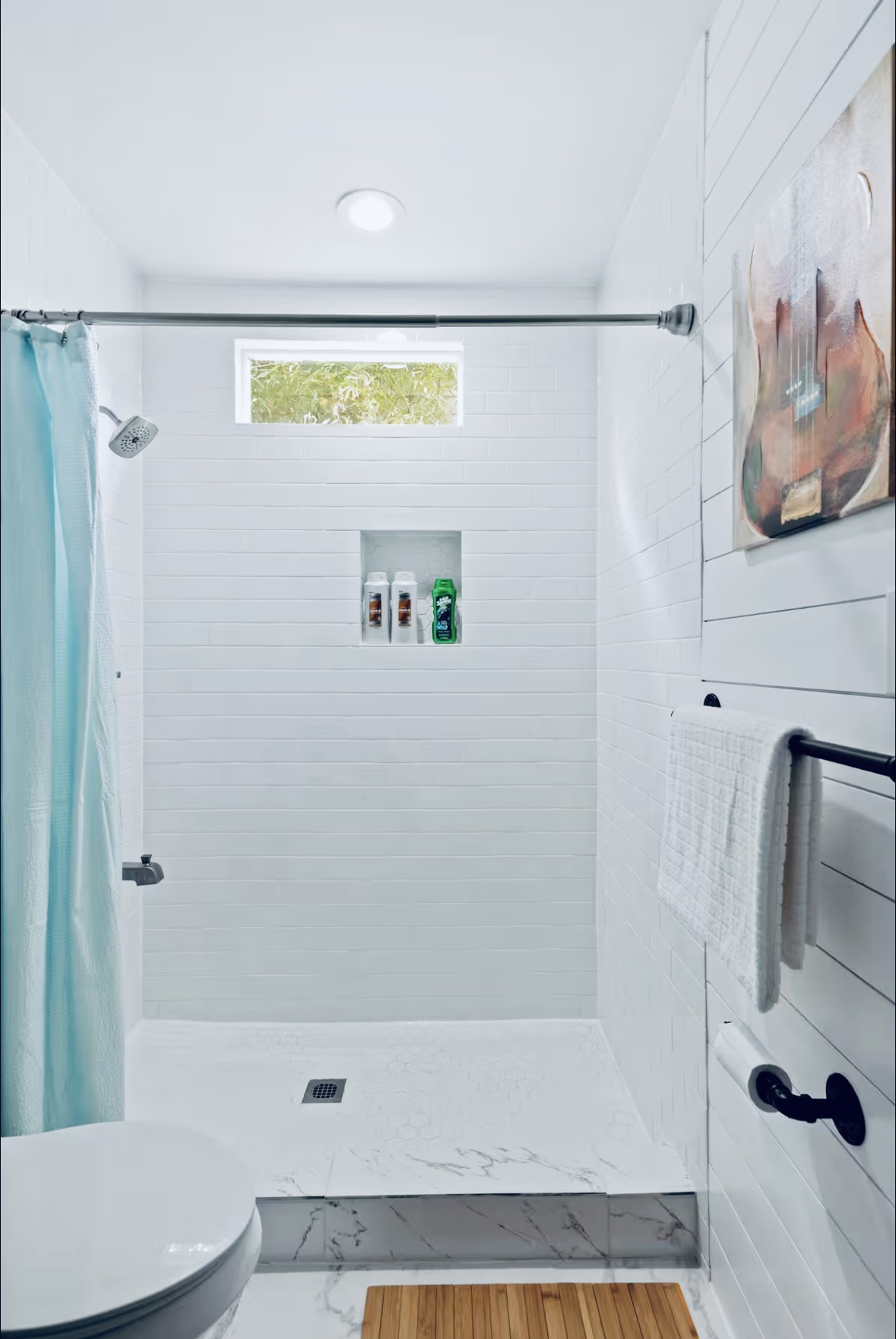 307 East 35th Street, Unit A Austin, TX 78705 - Photo 30 of 31 A well-lit shower features sleek white tile and a convenient inset shelf.
