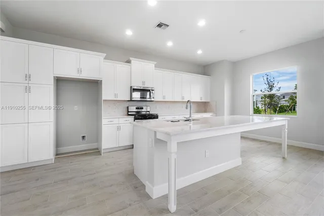 a kitchen with white cabinets and sink