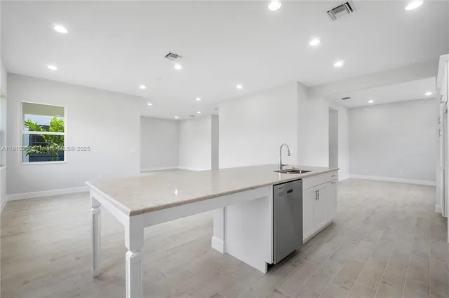 a kitchen with stainless steel appliances granite countertop a sink and a stove top oven with wooden floor