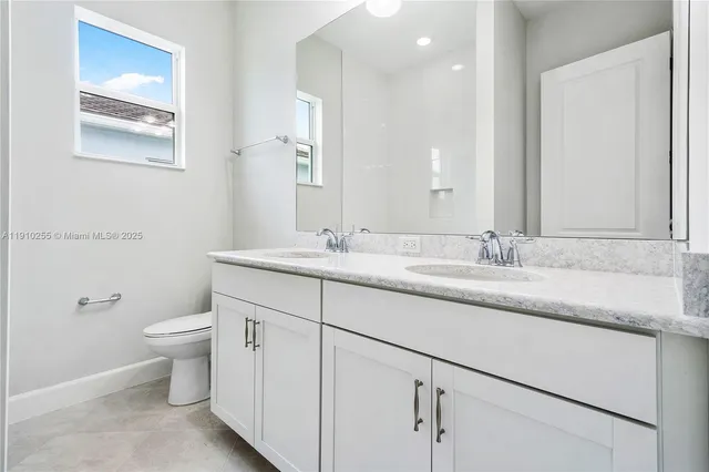 a bathroom with a granite countertop sink a toilet and a mirror