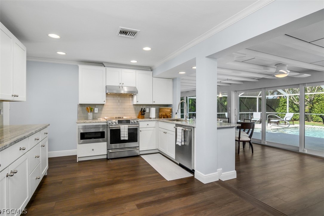 549 7th Avenue North Naples, FL 34102 - Photo 17 of 19 a kitchen with granite countertop a stove top oven a sink a dining table and chairs