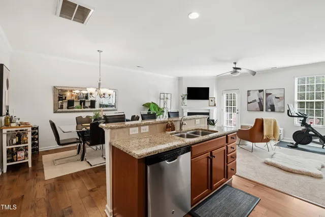 a living room with stainless steel appliances kitchen island granite countertop a sink a stove and a wooden floors