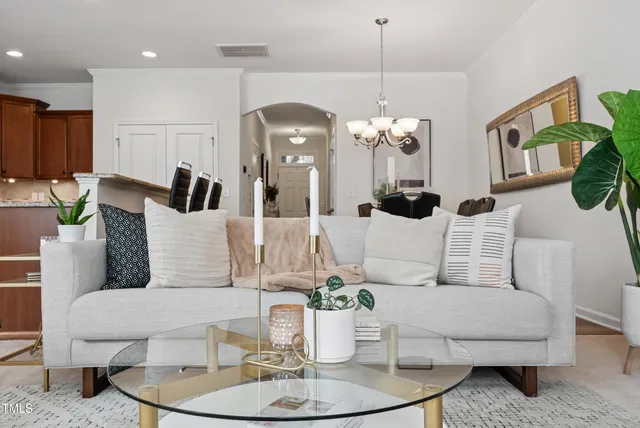 a living room with furniture a chandelier and kitchen view