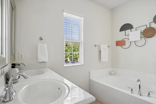 a bathroom with a white tub a sink and a window