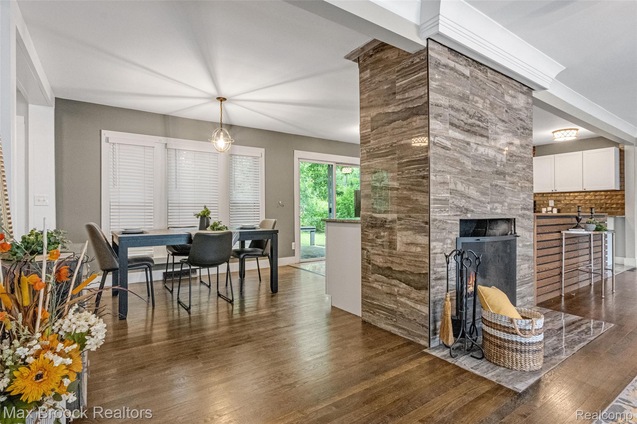 2905 Lahser Road Bloomfield Hills, MI 48304 - Photo 15 of 28 Open-concept living space featuring wood-finish flooring, a contemporary fireplace with stone-look tile surround, and a dining area with a modern light fixture
