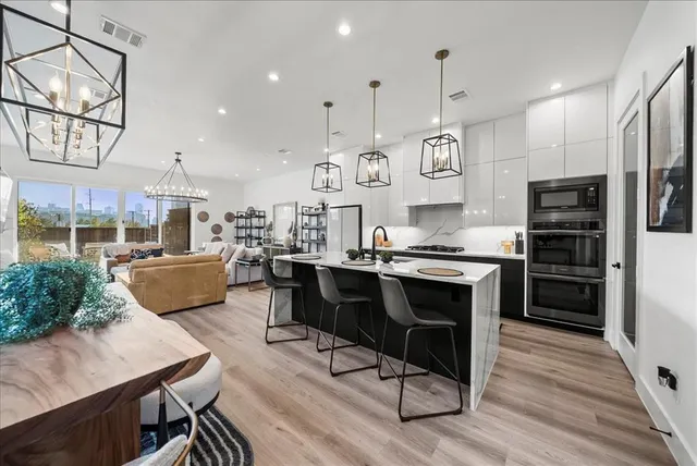 a dining room with wooden floor a chandelier a glass table and chairs