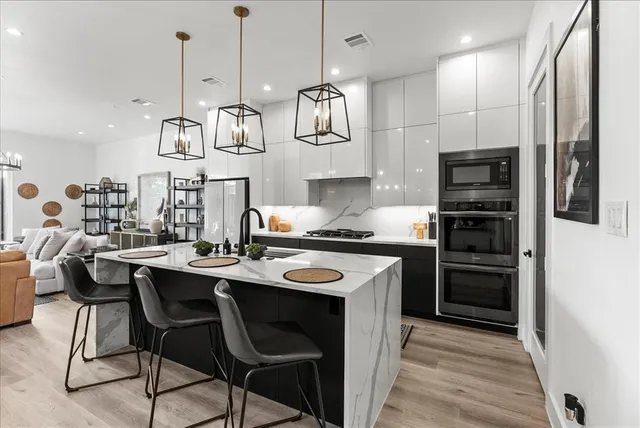 a kitchen with stainless steel appliances granite countertop a sink a stove and a wooden floors