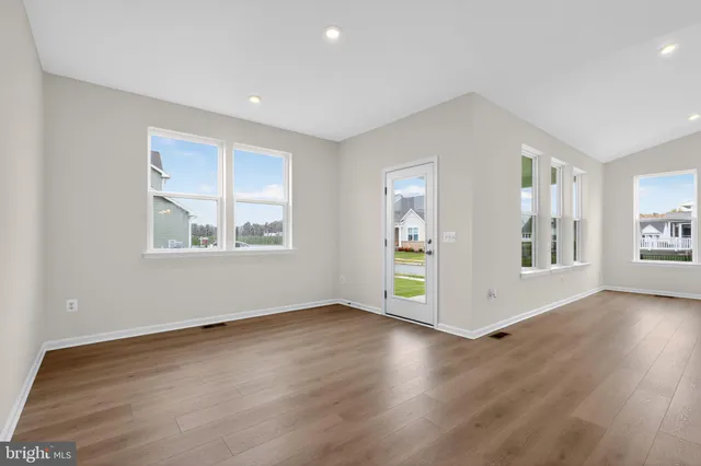 a view of an empty room with window and wooden floor