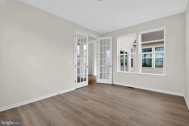 an empty room with wooden floor and windows