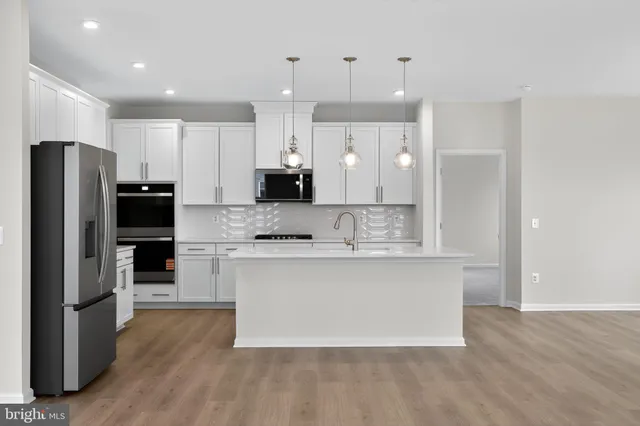 a large kitchen with stainless steel appliances kitchen island a large counter top and wooden floors