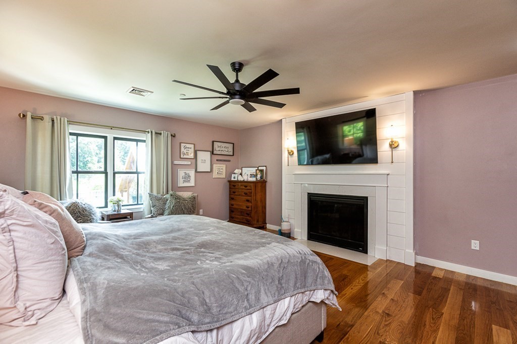 6 Twin Hills Farm Road, Unit 2 Rowley, MA 01969 - Photo 16 of 42 a spacious bedroom with a large bed a flat tv screen and a fireplace