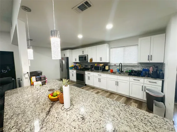 a kitchen with a refrigerator sink cabinets and wooden floor
