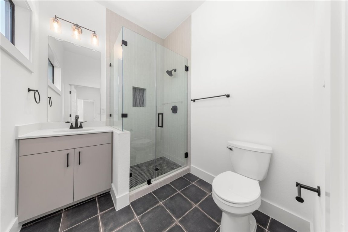 102 Mountain Home Road Horseshoe Bay, TX 78657 - Photo 17 of 32 a bathroom with a granite countertop toilet sink shower and mirror