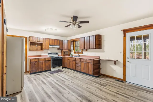 a kitchen with stainless steel appliances a stove top oven a sink dishwasher and a refrigerator with wooden floor