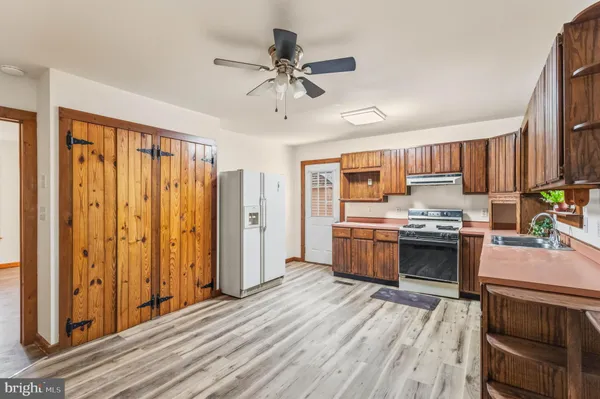 a kitchen with stainless steel appliances a stove top oven a refrigerator cabinets and wooden floor