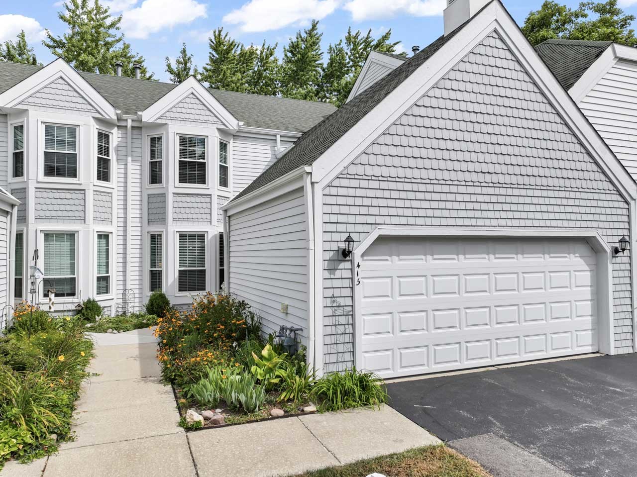 a view of a white house with a yard and potted plants