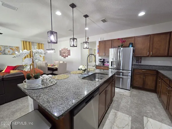 a kitchen with granite countertop kitchen island stainless steel appliances a sink stove and refrigerator