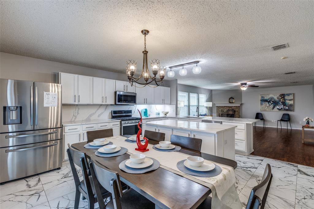 1425 Ridgecrest Drive Little Elm, TX 75068 - Photo 11 of 27 a kitchen with kitchen island granite countertop stainless steel appliances cabinets a dining table and chairs