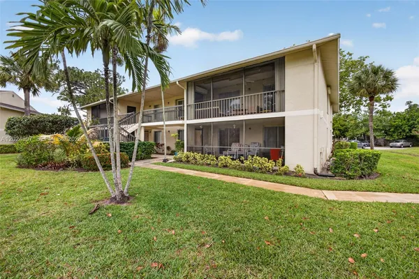 a view of a house with a yard and palm trees