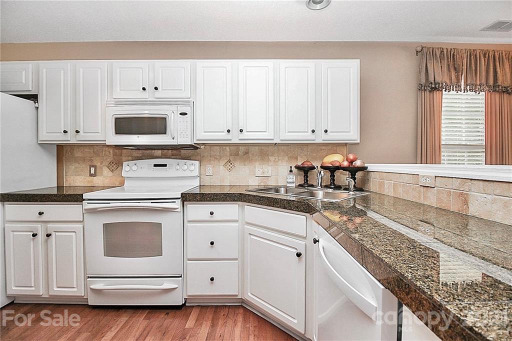 16844 Timber Crossing Road, Unit 2111 Charlotte, NC 28213 - Photo 3 of 33 a kitchen with granite countertop white cabinets and white appliances