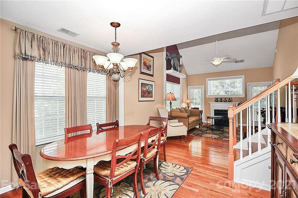 16844 Timber Crossing Road, Unit 2111 Charlotte, NC 28213 - Photo 5 of 33 a dining room with wooden floor a chandelier a wooden table and chairs