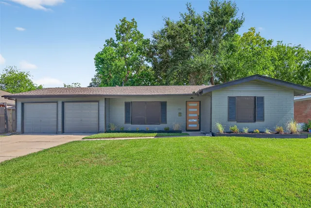 a house that is sitting in the grass with tress in the background