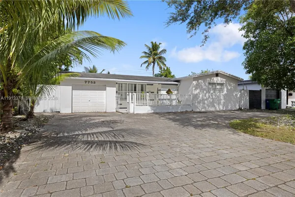 a view of a white house with a yard and palm trees