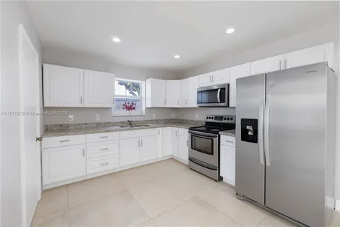 a kitchen with granite countertop white cabinets and stainless steel appliances
