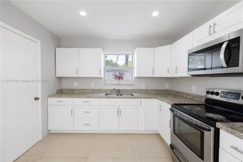 a kitchen with granite countertop white cabinets stainless steel appliances and a sink