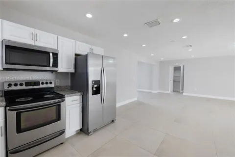 a kitchen with stainless steel appliances white cabinets and stove top oven