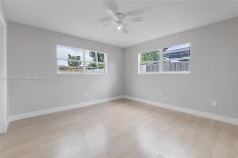 an empty room with windows and ceiling fan