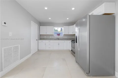 a large kitchen with a refrigerator a sink and a stove top oven
