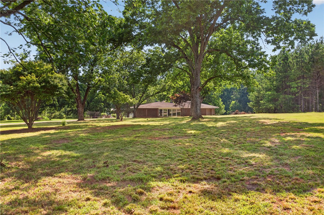 1412 Simpson Road Pendleton, SC 29670 - Photo 41 of 48 Mature trees frame a charming home set back on a generous grassy parcel, offering tranquil privacy.