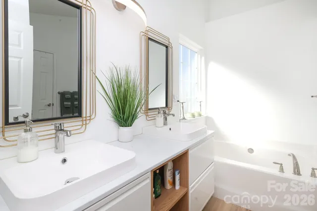 a bathroom with a double vanity sink a mirror and a bathtub