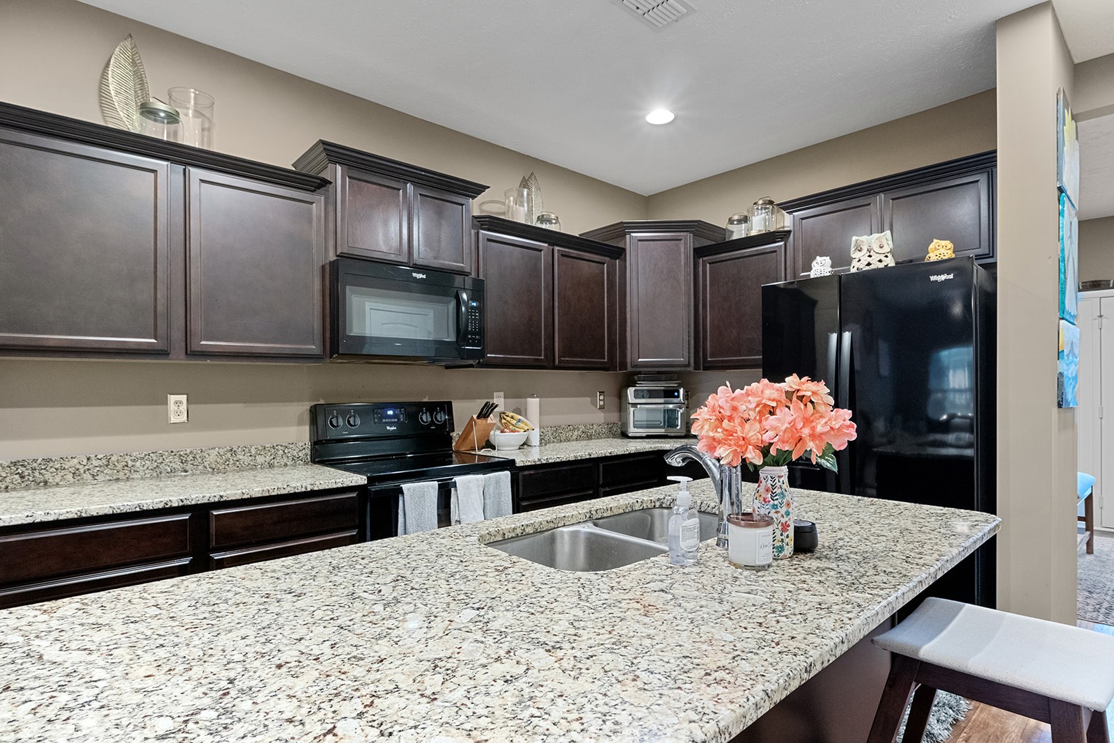 a kitchen with stainless steel appliances kitchen island granite countertop a sink cabinets and wooden floor