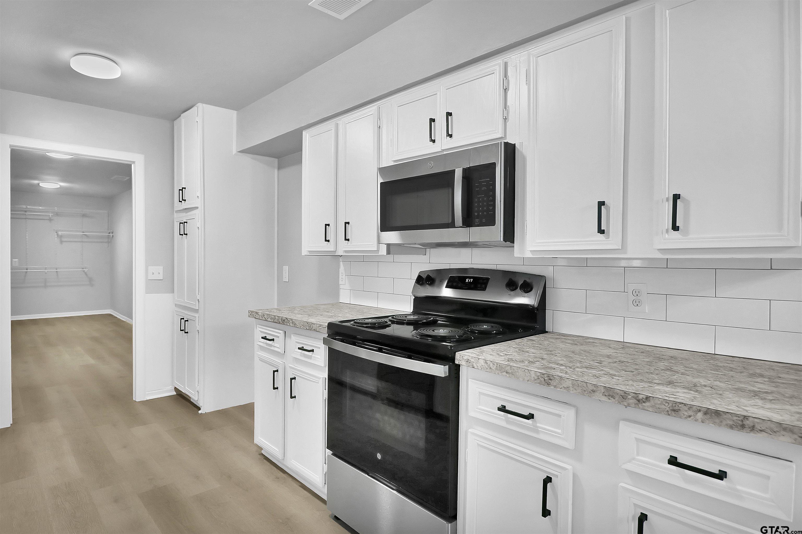 1310 Ridgeview Drive Tyler, TX 75701 - Photo 14 of 30 a kitchen with stainless steel appliances granite countertop white cabinets and black stove top oven with granite countertops