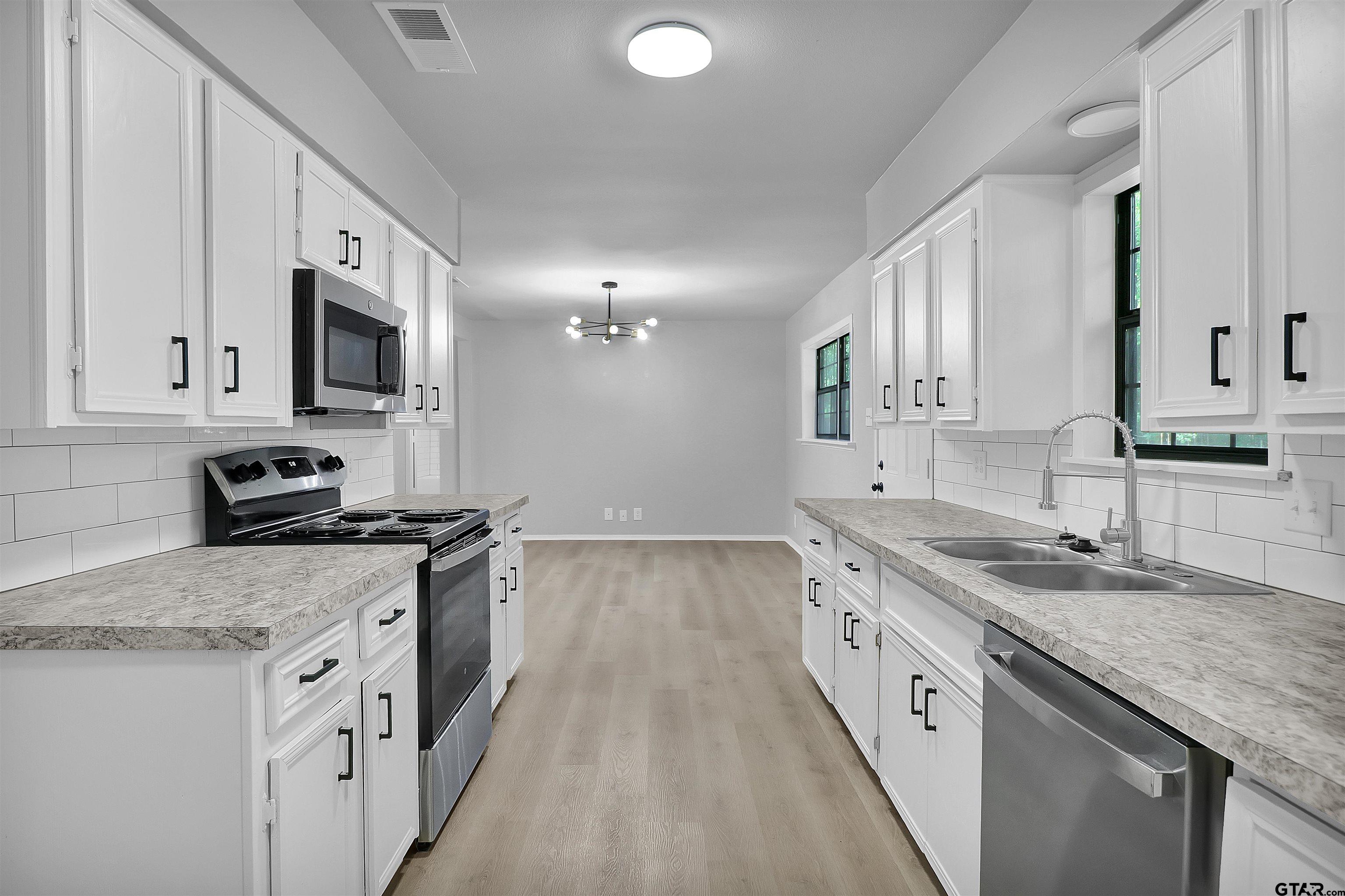 1310 Ridgeview Drive Tyler, TX 75701 - Photo 16 of 30 a kitchen with granite countertop a sink stove and cabinets