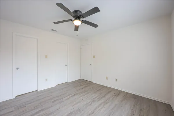 an empty room with wooden floor and a ceiling fan