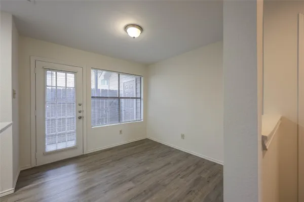 an empty room with wooden floor and windows with curtains view